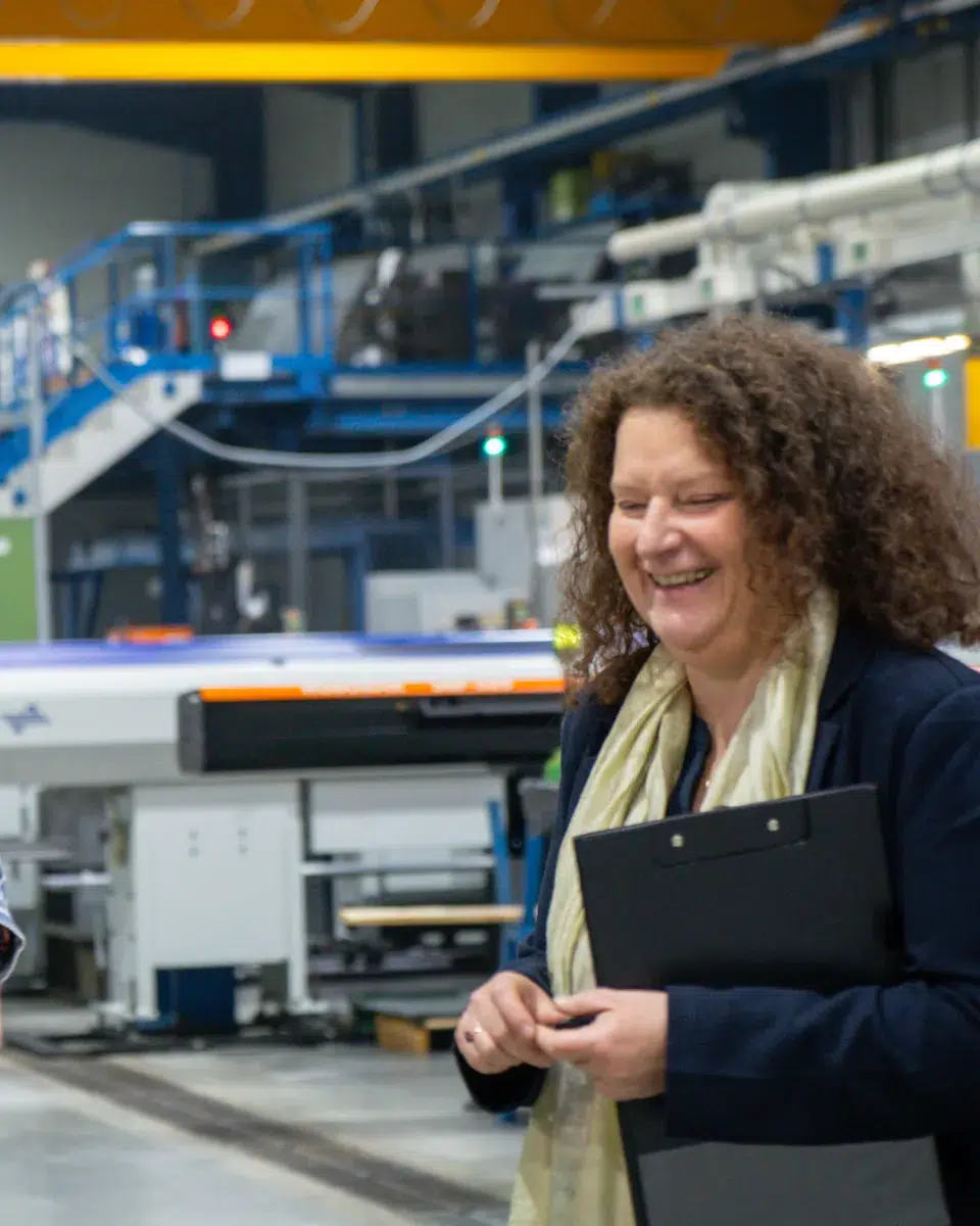Anne Dumarcher souriante sur le terrain, dans un atelier de production